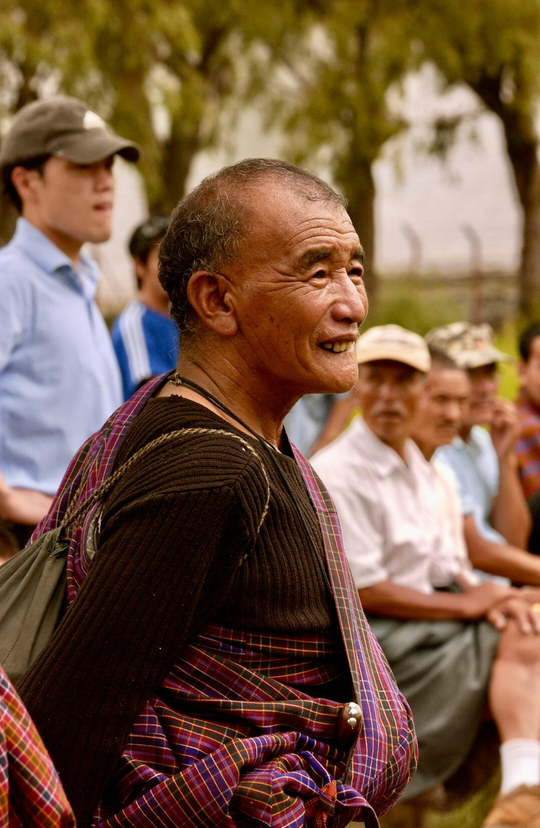 Older man with grey hair and a kind smile wearing a checked shirt