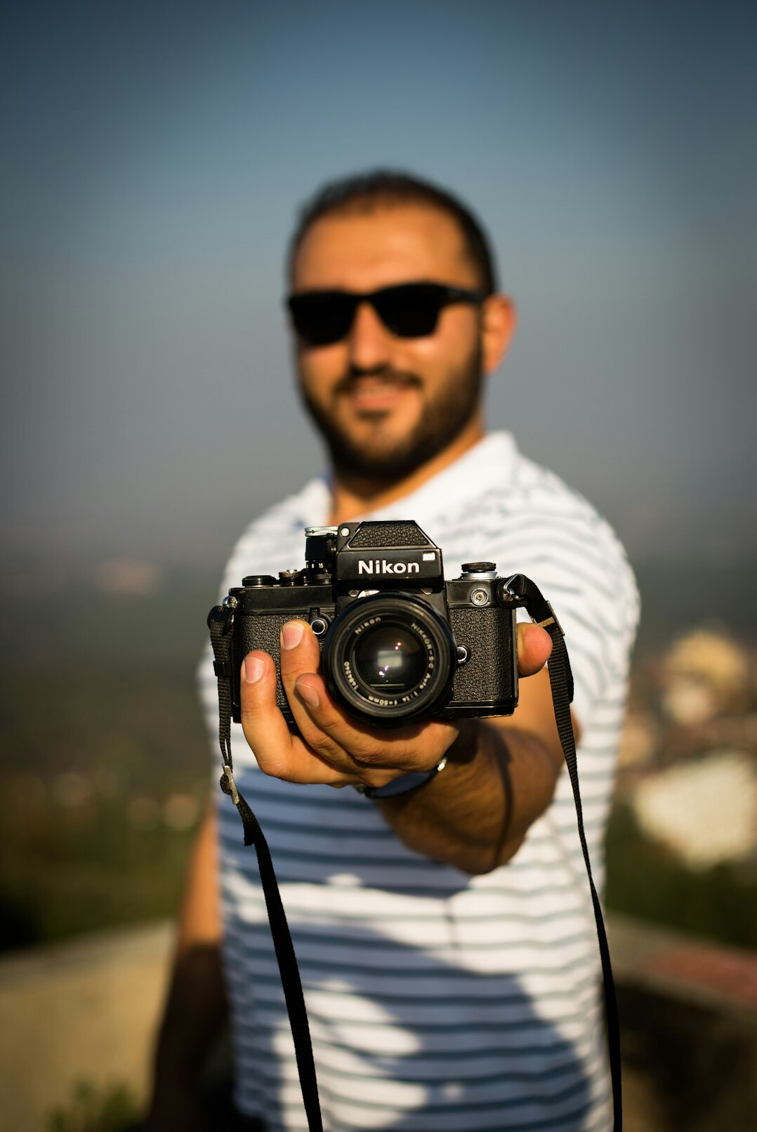 Smiling bearded man with glasses holding a studio camera