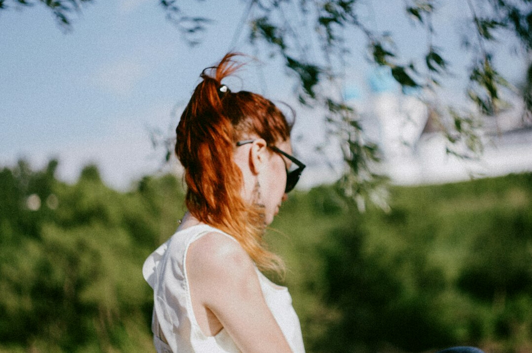 Woman in her early thirties with red hair and glasses smiling